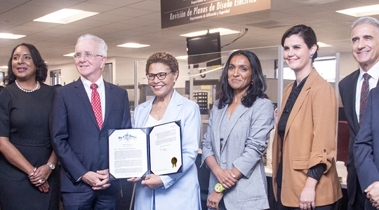 Mayor Bass holding Executive Directive 7 alongside dignitaries