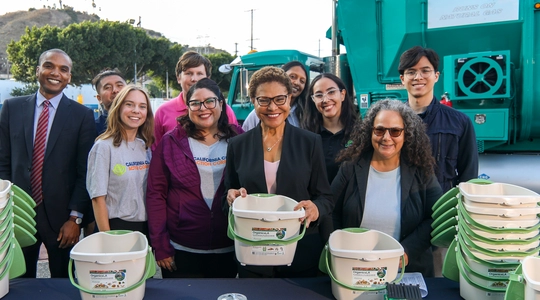 Mayor Bass holding a green pail for composting